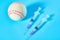 Baseball ball near syringe on blue background. Concept of doping in professional sport