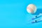 Baseball ball near syringe on blue background. Concept of doping in professional sport