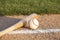 Baseball and bat laying on basepath with grass infield