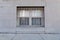 Basement window with metal security bars, gray stone exterior, sidewalk
