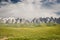 At-Bashi Mountain peaks with snow, green pastures under stormy sky in Kyrgyzstan