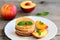 Basic pancakes with syrup and grilled nectarines on a serving plate and an old wooden table. Pancake recipe without butter