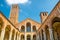 Basilica of Sant`Ambrogio church brick building with bell towers, courtyard, arches, blue sky background, Milan