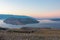 Baska - Panoramic sunrise view of deserted island Prvic seen from idyllic hiking trail near coastal town Baska