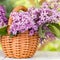 Basket with a bouquet of lilac flowers on a white wooden table in the summerhouse in the garden