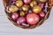 Basket of colored eggs on white wooden table.