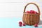 Basket of delicious fresh ripe raspberries on blue wooden table against white background, space for