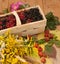 A basket filled with ripe berries and a bouquet of filed flowers on a wooden surface decorated with hips and autumn leaves