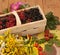 A basket filled with ripe berries and a bouquet of filed flowers on a wooden surface decorated with hips and autumn leaves