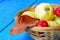 Basket with fresh apples and plums on blue wooden background