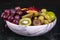 Basket of fresh tropical fruitson in bowl on black marble background.