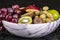 Basket of fresh tropical fruitson in bowl on black marble background.