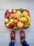 Basket full of fruit on the floor with person standing next to it