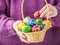 Basket full of multicolored easter eggs in hands pensioner woman