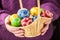 Basket full of multicolored easter eggs in hands pensioner woman