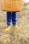 Basket, jeans and brown leather shoes on the legs, against the background of autumn grass, the concept of changing the season