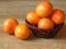 A basket of orange shiny ripe grapefruit fruit on oak tree background. Retro rustic style. Tropical fruit Citrus Ã— paradisi.