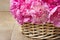 Basket of pretty pink peonies, wooden rustic background,