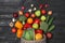 Basket with scattered fruits and vegetables on black wooden table