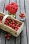 Basket of strawberries on wooden table. Bouquet of red roses in