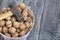 A basket with walnuts. There is a hammer on them. On a painted pine board surface