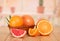 Basket with whole grapefruit and orange, the leaves and the pieces near kitchen background.