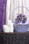 A basket, woven from a vine, filled with gifts and flowers. On a light background. Nearby are decorative candles.