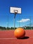 A basketball ball lies in front of a basketball ring at the stadium.Basketball court in the open air with artificial surface. Hold