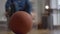 Basketball ball in living room indoors with unrecognizable blurred disabled young man rolling wheelchair leaving with