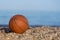 Basketball ball lying on the sand by the sea at sunset