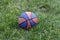 Basketball ball waiting for children. Green grass and worn basketball ball.