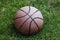 Basketball ball waiting for children. Green grass and worn basketball ball.