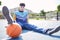 Basketball, fashion and portrait of a trendy model sitting on the floor of outdoor court. Edgy, stylish and cool man or