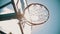 A basketball hoop. The net fluttering in the wind. Bright sunlight