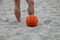A basketball is lying on the sand against the background of men`s feet