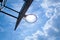 Basketball ring on the background a blue sky with white clouds and bright sun. Basketball hoop on a shield on an outdoor sports