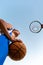 Basketball. A teenager in blue sportswear holds a ball in his hands and looks at a basketball Hoop. Bottom view. Sky in the