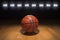 Basketball on wood floor beneath bright lights