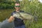 Bass fishing. Big bass fish in hands of pleased fisherman. Largemouth perch at pond