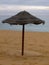 Bast parasol on the sandy beach with bad weather