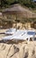 Bast parasol and white plastic sunbeds on the beach