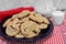 A batch of chocolate chip walnut cookies on a plate with a glass