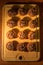 Batch of cupcakes with chocolate frosting on wooden board