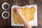 Batch of fresh cooked sugar cookies on parchment paper, womanâ€™s hand putting chocolate on cooki