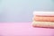 Bath accessories - towels folded, stacked on a light, bright blue and pink background The concept of caring for yourself, your bod