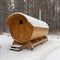 Bath barrel on a background of a winter forest. The first fluffy snow is falling