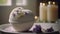 a bath bomb sitting on top of a white plate next to a candle and some flowers on a table next to a candle and some candles.