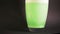 Bath salt green dissolves in vase of water in slow mo with particle drilling
