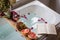 Bath tub with a tray with grapefruit slices, bunch of grapes, a glass of wine and a book