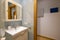 Bathroom with cherry wood cabinet with integrated mirror, cream-colored marble